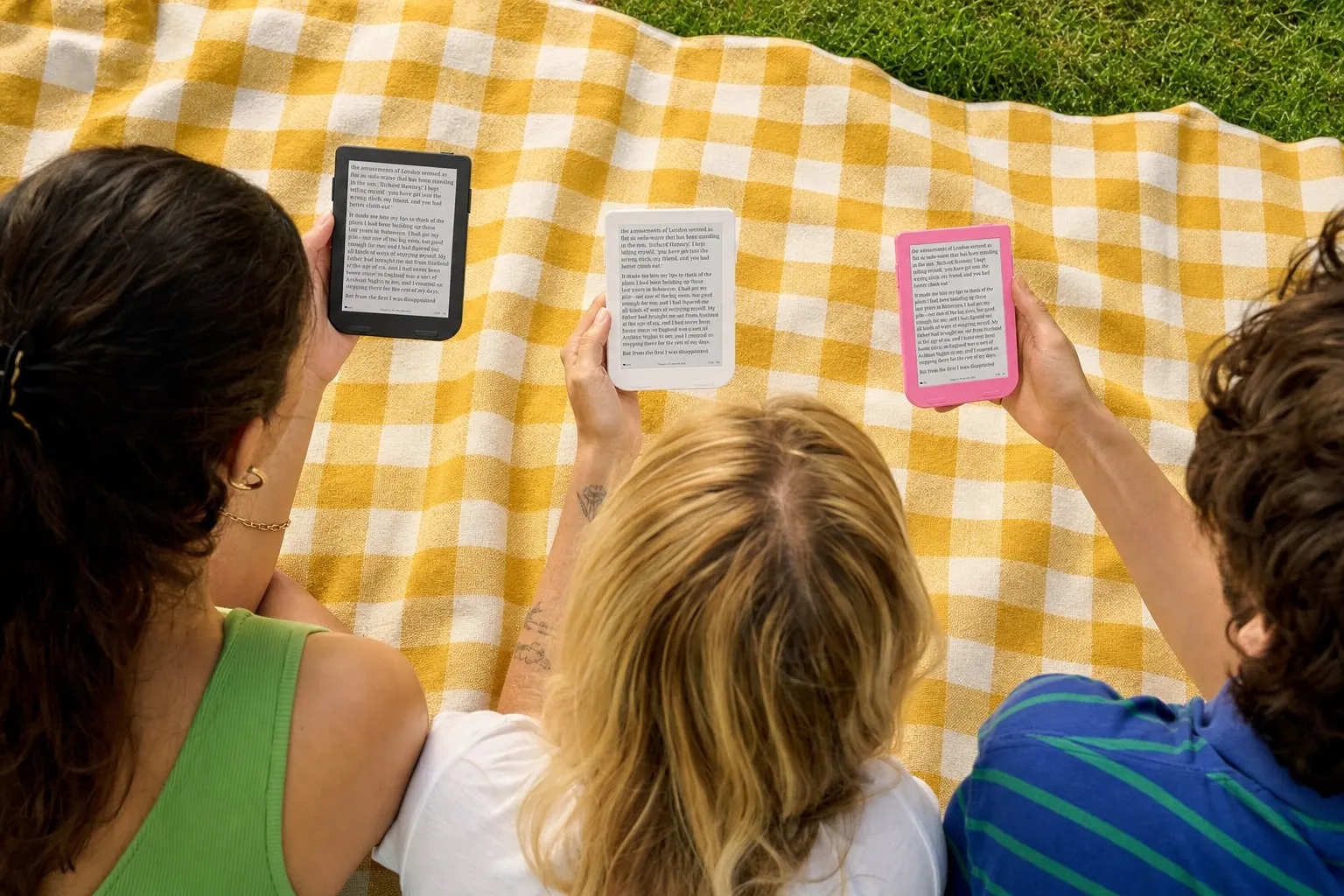 Three friends reading Snug Minis on a picnic blanket
